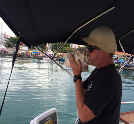 Le skipper soufflant une corne de brume Maiso lors du départ de l'excursion au Grand Cul-de-Sac Marin